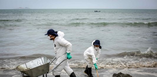 En la fotografía, trabajadores laboran en el retiro de petróleo de la arena de la playa de Ancón, en el norte de Lima.