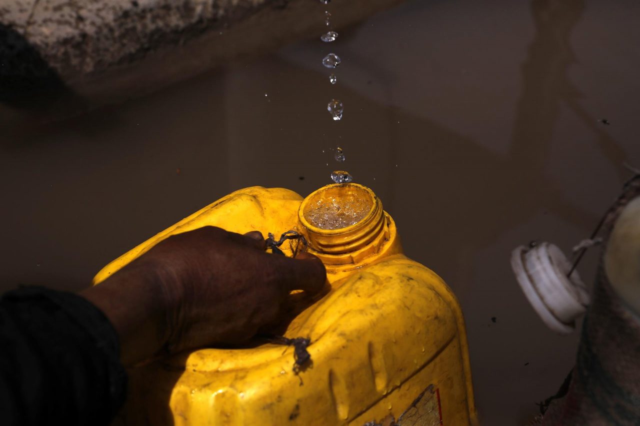 Una mujer llena de manera penosa un recipiente con agua en África, donde el recurso hídrico potable es escaso.