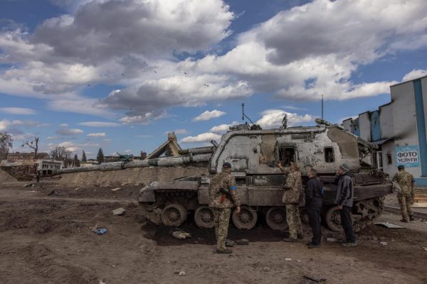 Soldados ucranianos observan los restos de un destruido vehículo de combate ruso.