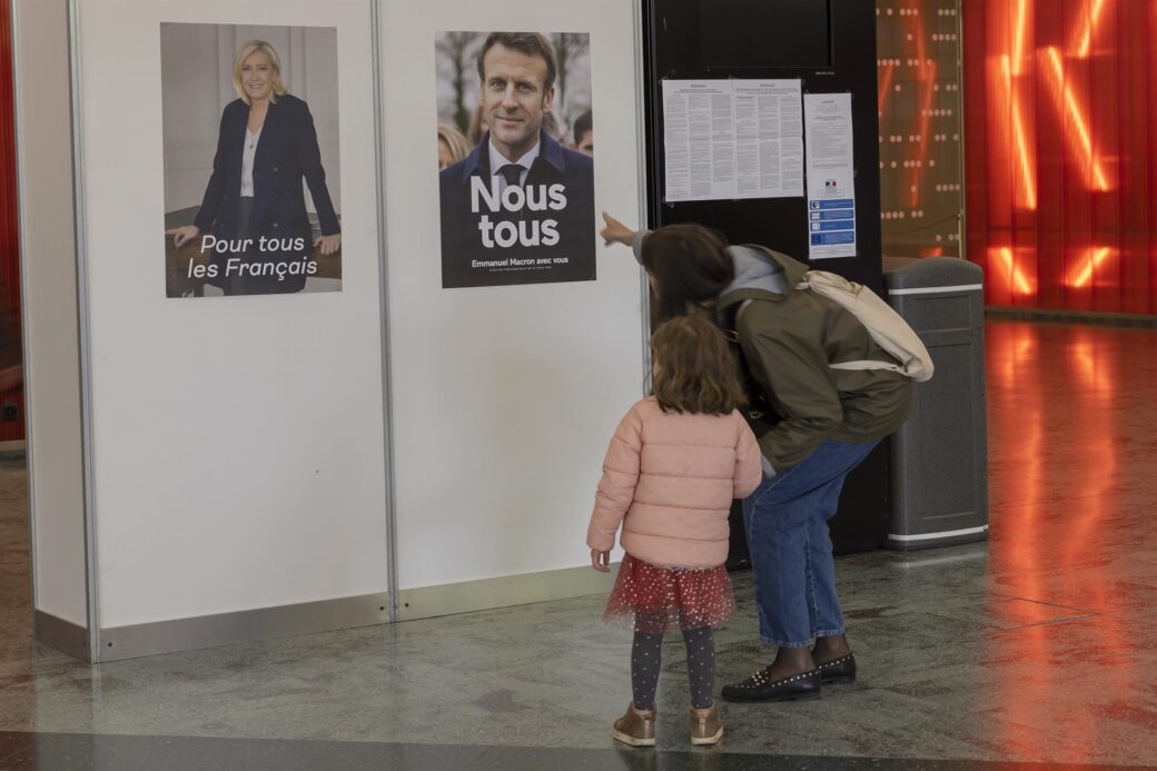 Un votante muestra a su hija los carteles electorles de los candidatos a la presidencia francesa.