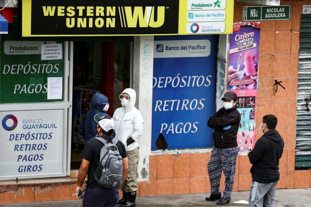 Personas hacen fila afuera de una agencia de Western Union en Quito.