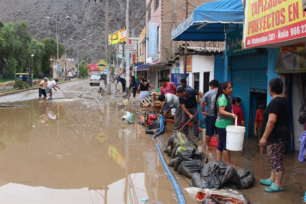 Residentes de Chaclacayo, en Lima, intentan sacar el agua de sus casas y locales inundados.
