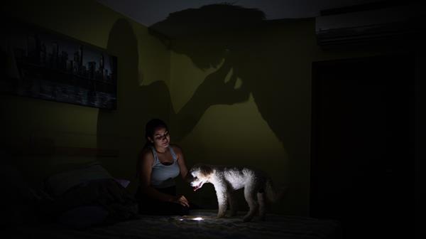 Una persona juega con su mascota en un apartamento sin electricidad en Maracaibo (Venezuela). EFE