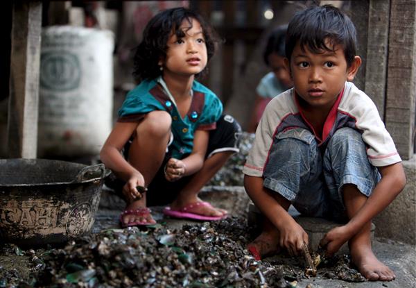 Hambre. Niños abren ostras en un área pobre del norte de Yakarta (Indonesia).