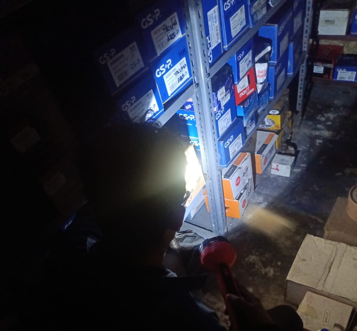 Uno de los trabajadores de un local de repuestos intentando encontrar un pedido en medio de la oscuridad.