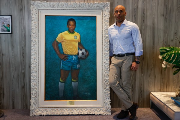 Edinho, hijo de Pelé, posa junto a un retrato de su padre durante una entrevista con EFE, en el Museo Pelé, en la ciudad de Santos