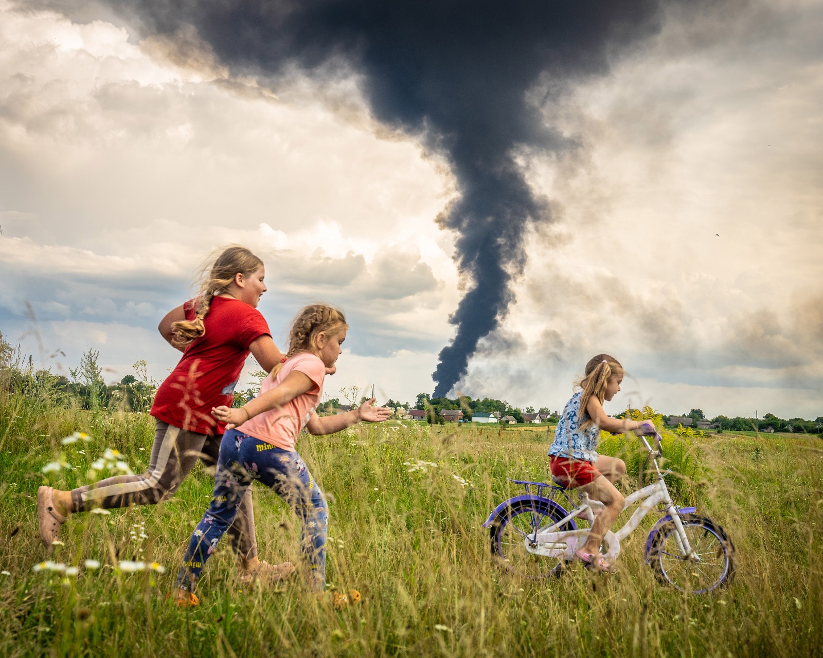 Una imagen de una niña en bicicleta junto a dos amigas en un prado en el noroeste de Ucrania, en "un momento de despreocupación bajo las oscuras nubes de la guerra", es la ganadora del concurso internacional en el que el Fondo de las Naciones Unidas para la Infancia (UNICEF) en Alemania elige la mejor foto del año. EFE/ Patryk Jaracz/UNICEF SOLO USO EDITORIAL/SOLO DISPONIBLE PARA ILUSTRAR LA NOTICIA QUE ACOMPAÑA (CRÉDITO OBLIGATORIO)