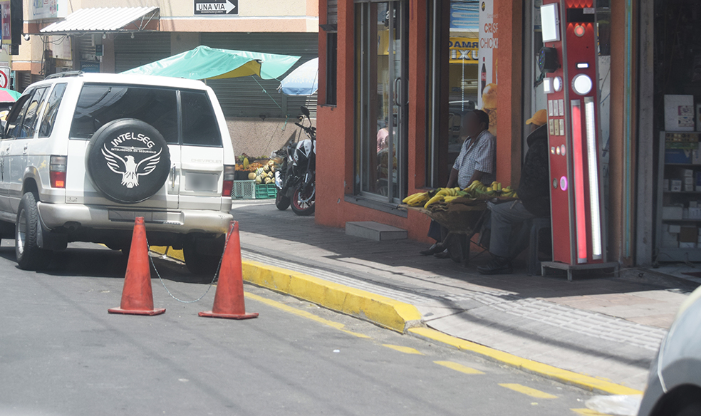 Los propietarios de negocios colocan sillas, cajas y conos para reservarse un parqueadero en la vía pública.
